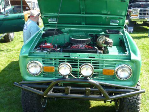 1995 Ford Bronco - Front view of a green first-generation Ford Bronco with its hood open, revealing the engine bay.