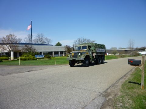 1995 Ford Bronco - A military truck drives past a building with a FLEX sign and an American flag flying.