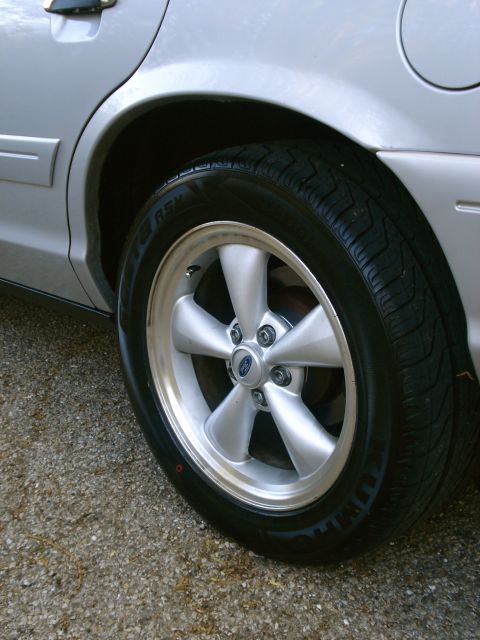 2000 Ford Crown Victoria - Close-up of a silver sedan's rear wheel and tire, a five-spoke rim.