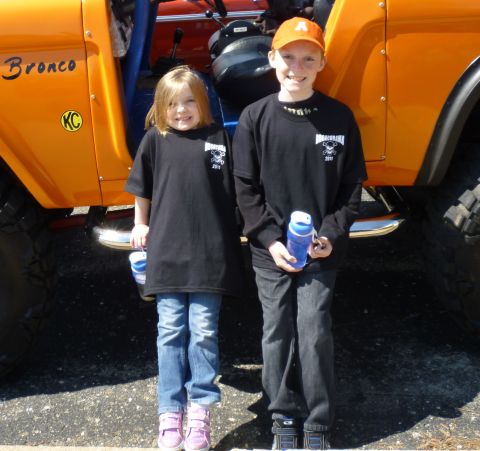 1995 Ford Bronco - Two children pose in front of an orange Ford Bronco, identified by the script on its fender.