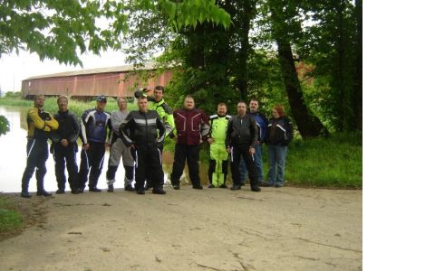 1985 Ford Crown Victoria LTD - Ten people in motorcycle gear pose for a photo in front of a covered bridge and a body of water.