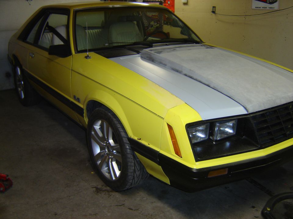 Yellow 1979 Ford Mustang coupe with grey hood scoop and 5.0 badge