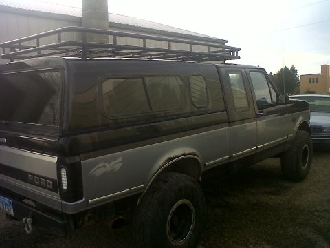 1994 Ford F-150 - This pickup truck has a two-tone paint scheme and a camper shell with a roof rack.