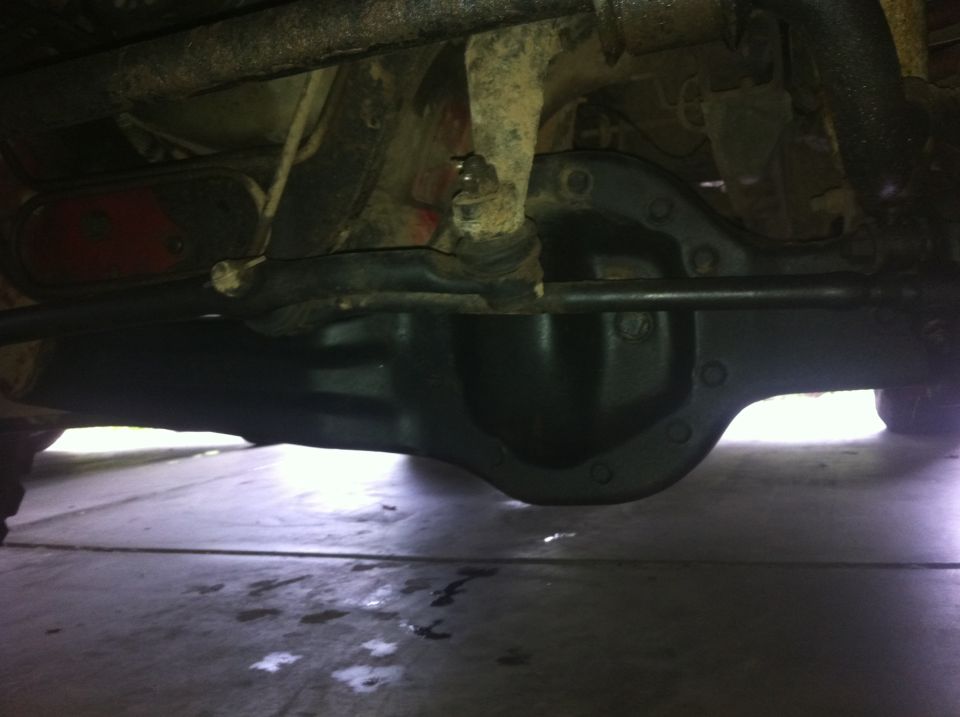 Underside of a vehicle showing a differential, suspension arms, and a red taillight