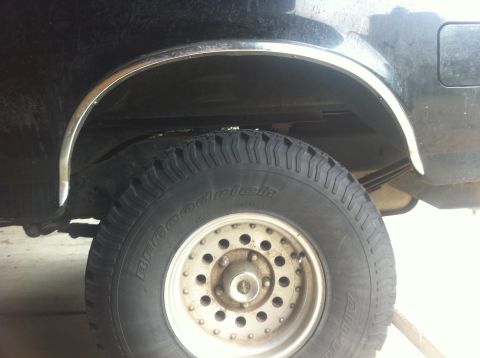 1990 Ford Bronco - A close-up view of the rear tire and wheel well of a vehicle, with visible suspension components.