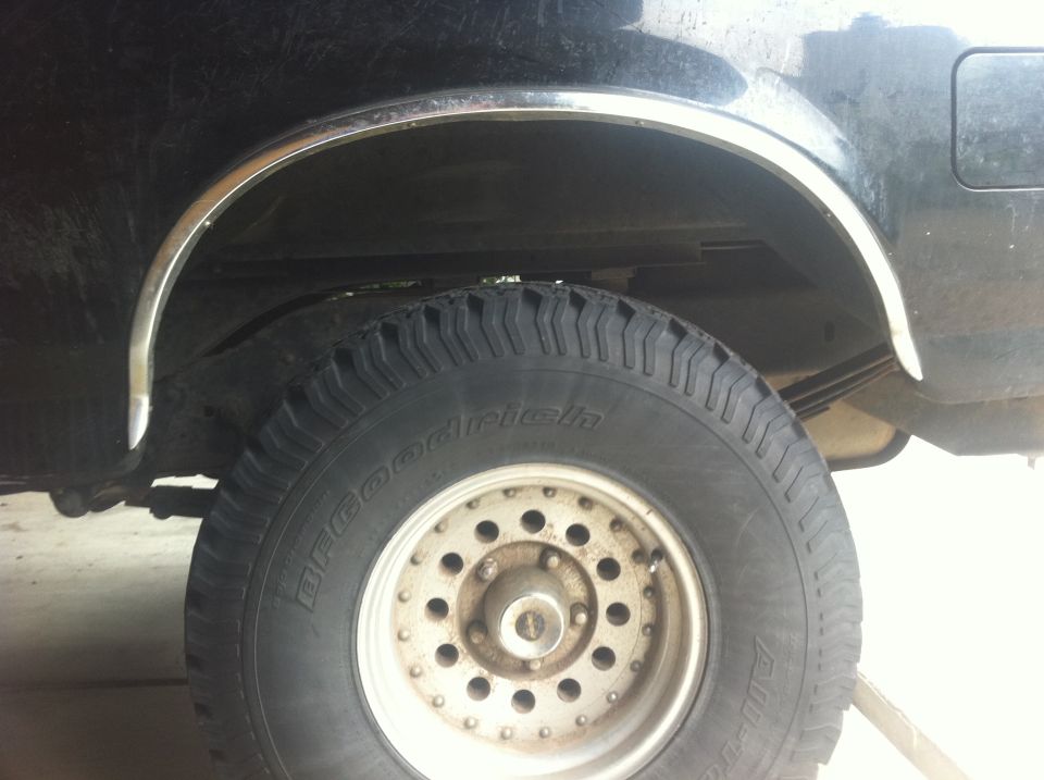 Close-up of a vehicle's rear tire and wheel well, showing a BFGoodrich tire and chrome trim around the wheel opening