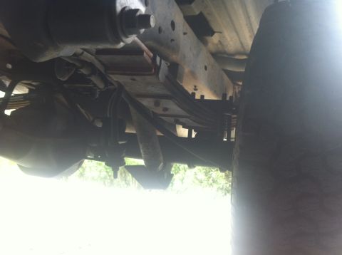 1990 Ford Bronco - This photo shows the underside of a vehicle, focusing on the rear suspension components and a large tire.
