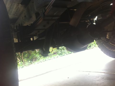 1990 Ford Bronco - Undercarriage view of a lifted vehicle, highlighting suspension components and a tire.