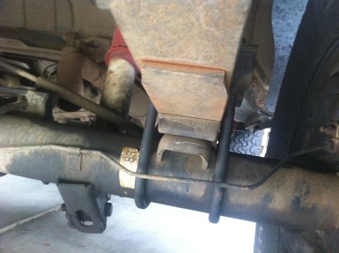 1990 Ford Bronco - Close-up view of the rear axle and leaf spring suspension system, a yellow sticker with the number '83'.