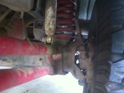 1990 Ford Bronco - Undercarriage view shows red-painted suspension components, including a shock and coil spring.