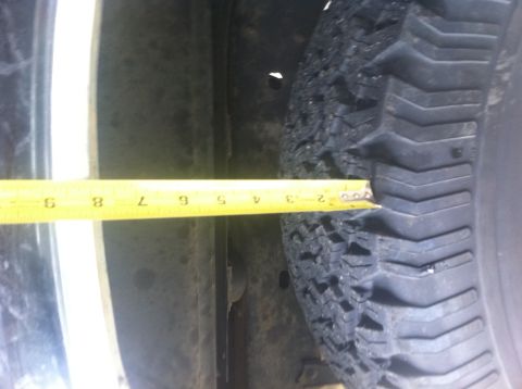 1990 Ford Bronco - A tape measure is used to gauge the clearance next to a tire, indicating a measurement of approximately 3 inches.