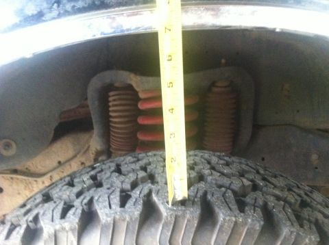 1990 Ford Bronco - Measuring suspension lift with a tape measure on a vehicle's tire.