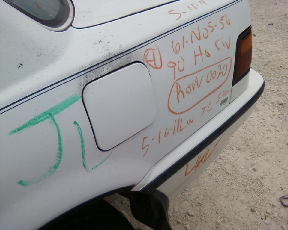 White car's rear quarter panel with graffiti and handwritten notes, including 'ROW 0020'