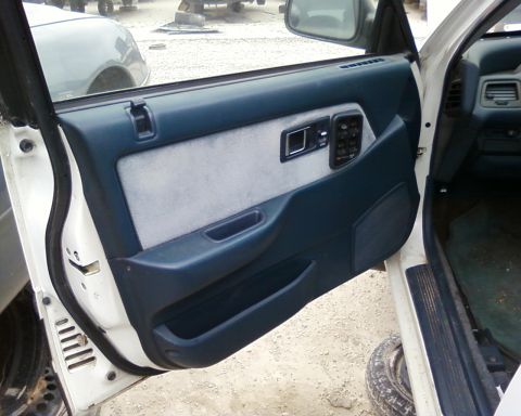 1991 Ford Festiva - Interior door panel of a vehicle, showing the armrest, window controls, and speaker.