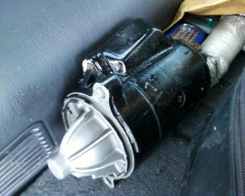1976 Ford Torino - A black starter motor with a silver end is resting on the floor of a vehicle.