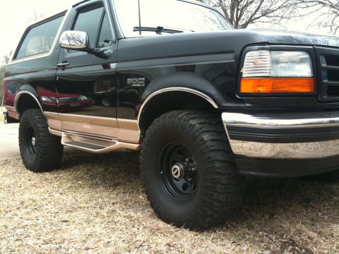 1996 Ford Bronco - This 1996 Ford Bronco features a black exterior with chrome accents and side steps, captured from a 3/4 front angle.