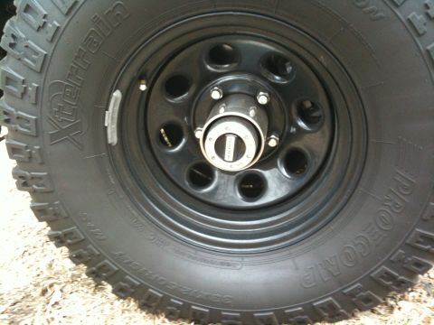 1996 Ford Bronco - Close-up of a BFGoodrich Xterrain tire and black wheel with a chrome hubcap.
