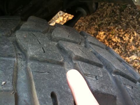 1996 Ford Bronco - Close-up of a tire tread showing wear and cracks, with a finger indicating damage.