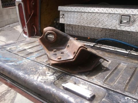 1978 Ford Bronco - A rusted metal suspension part is in the bed of a pickup truck next to a toolbox.