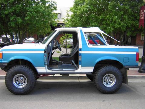 1996 Ford Bronco - Side view of a modified Ford Bronco with a two-tone paint scheme and off-road tires.