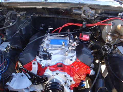 1989 Ford Bronco - The engine bay of a vehicle shows a V8 engine with custom red paint and numerous modifications.