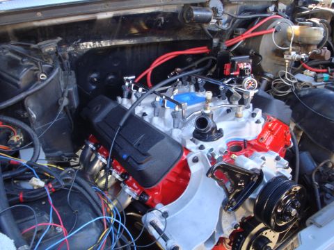 1989 Ford Bronco - Engine bay detail shot focusing on the V8 motor with custom red valve covers and headers.