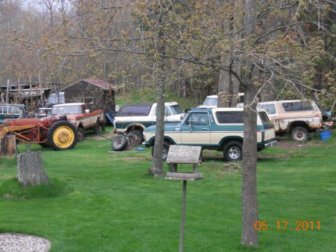 1978 Ford Bronco - A two-tone green and white 1978 Ford Bronco is visible among several other vehicles in a rural setting.