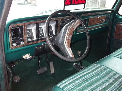 1978 Ford Bronco - The interior of a 1978 Ford F-Series truck, woodgrain trim and green plaid upholstery.