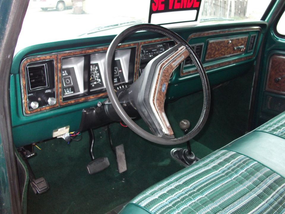 Interior shot of a green 1978 Ford F-Series truck dashboard and plaid seat