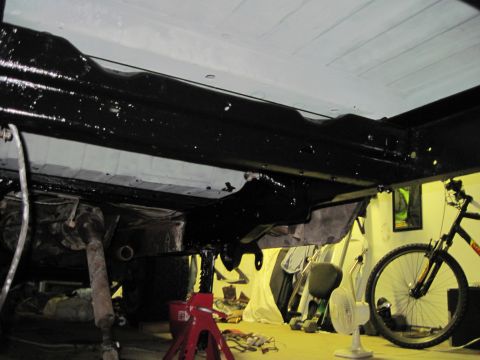 1979 Ford Bronco - The undercarriage of a vehicle is being worked on, with a bicycle in the background.