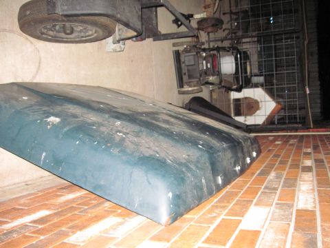1979 Ford Bronco - A vehicle hood and engine parts are stored on a brick patio.