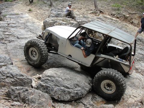 1967 Ford Mustang - A custom-built off-road vehicle navigates a rocky trail, with onlookers observing the challenging terrain.