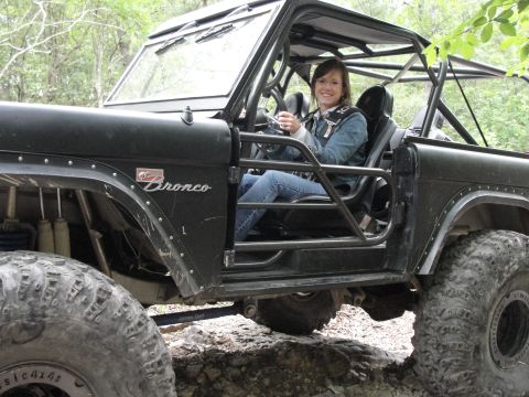 1967 Ford Mustang - A woman sits in the driver's seat of a modified black Ford Bronco off-road vehicle.