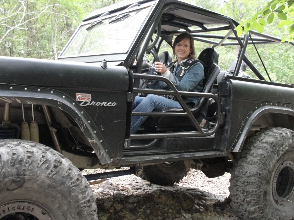 Black Ford Bronco with roll cage and off-road tires, driver seated inside
