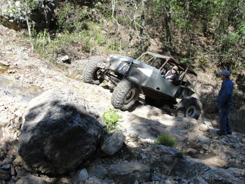 1967 Ford Mustang - A custom off-road buggy navigates a challenging rocky terrain with a spectator observing the climb.