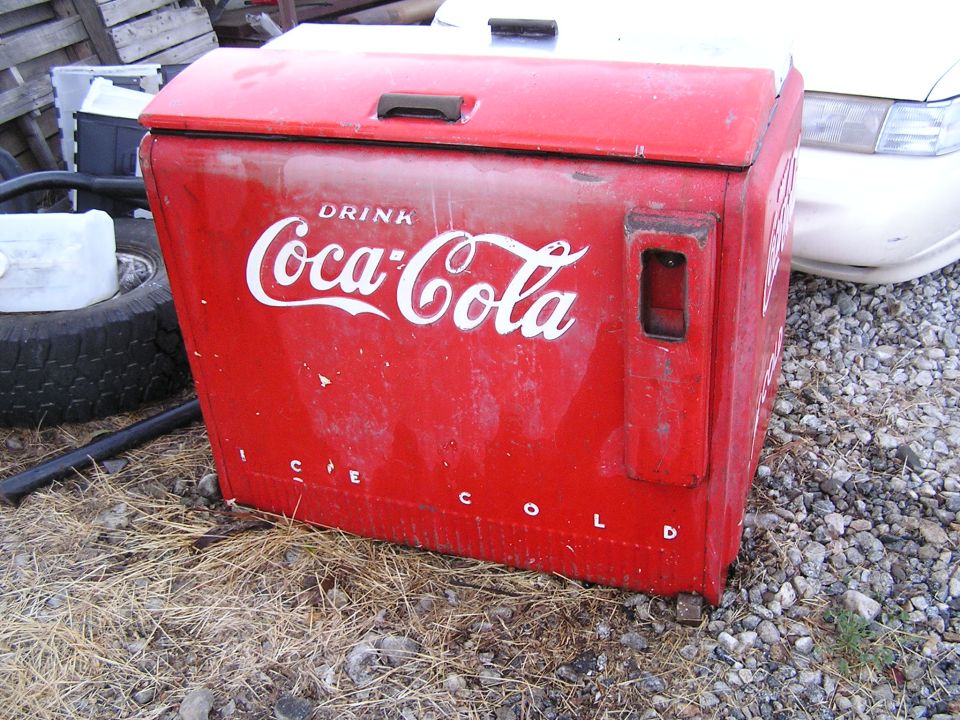 Vintage red Coca-Cola ice chest cooler sitting on gravel