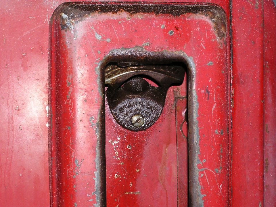 Cast-iron STARR X wall bottle opener on a worn red-painted metal panel