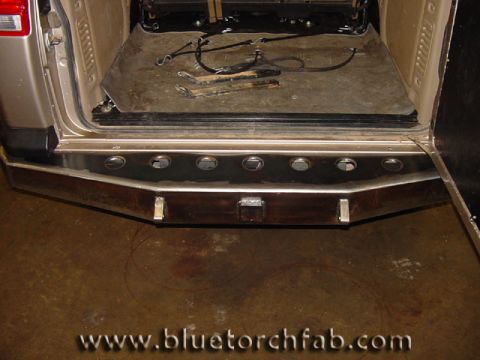 1996 Ford Bronco - The rear of an SUV shows a custom metal bumper with integrated lights and an open cargo area.