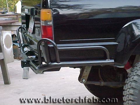 1996 Ford Bronco - Rear view of a black SUV with a custom roll cage bumper and visible leaf springs.