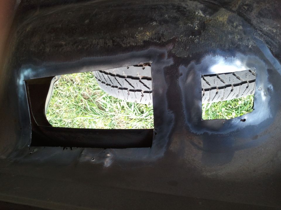 Spare tire visible through two square cutouts in dark metal