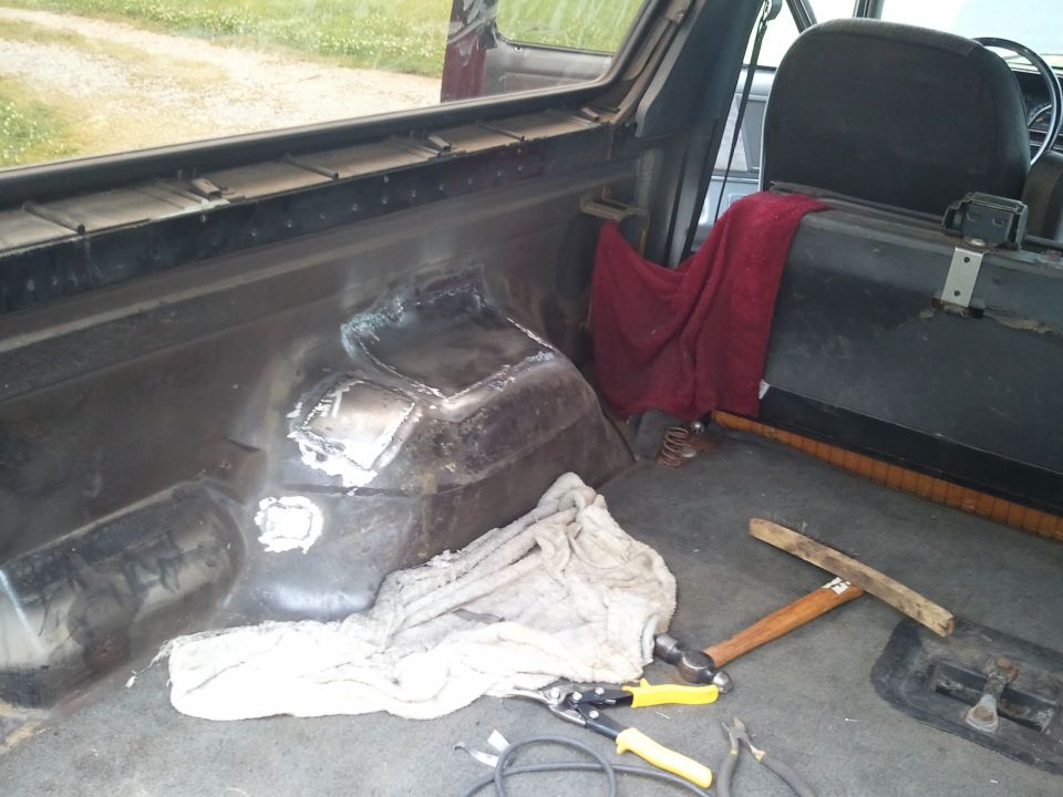 Interior view of a vehicle with metal patches on the floor and tools nearby