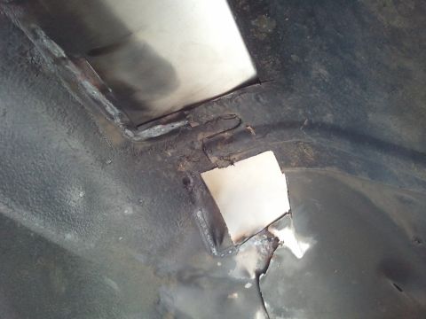 1989 Ford Bronco - Close-up view of a vehicle's undercarriage, revealing areas of rust and recent metal patch repairs.