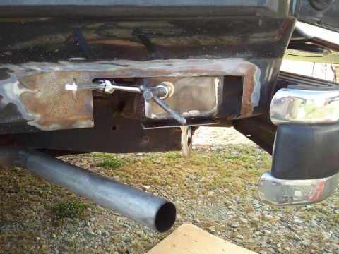 1989 Ford Bronco - Close-up of a vehicle's rear bumper and exhaust pipe, revealing rust and a repair bracket.