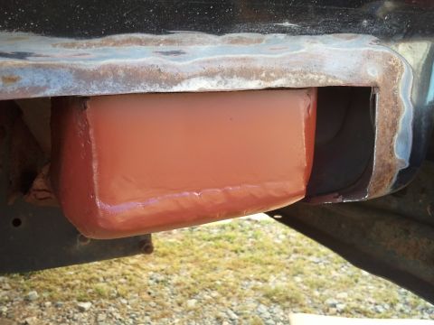 1989 Ford Bronco - Detail of a vehicle's undercarriage showing rust and a freshly primed repair section.