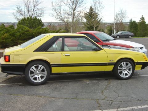 1979 Ford Mustang - Side view of a yellow 1979 Ford Mustang coupe parked in a lot with other vehicles.