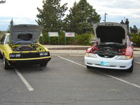 1979 Ford Mustang - Two Ford Mustangs, one from the 1980s and one from the 1990s, are parked side-by-side with their hoods open.