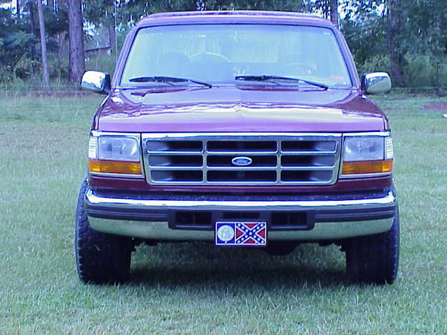 Front view of maroon Ford SUV on grass with Confederate flag front plate