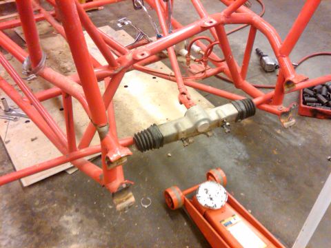 1995 Ford F-150 - The red tube frame chassis of a custom vehicle is shown with its steering rack assembly.
