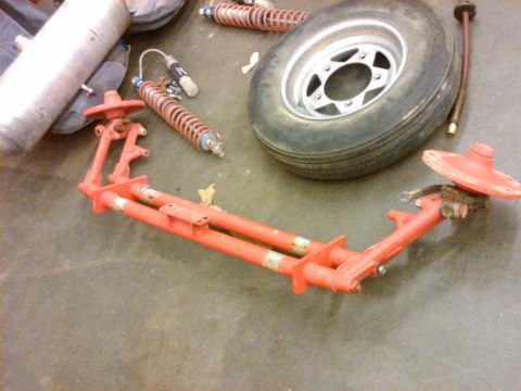 1995 Ford F-150 - Vehicle suspension components and a tire are laid out on a concrete surface.