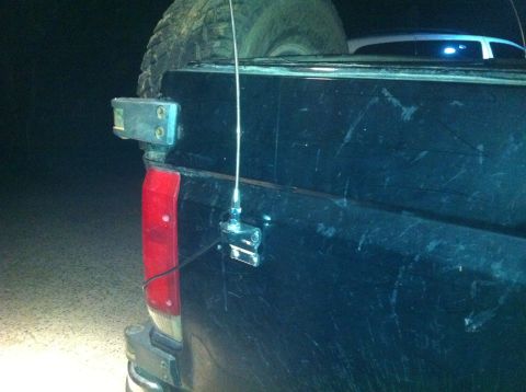 1990 Ford Bronco - The rear of a black pickup truck is shown at night, equipped with a spare tire and radio antennas.
